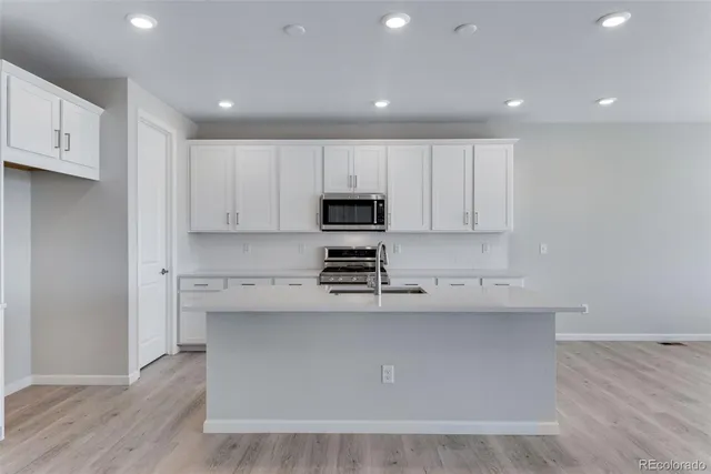 a kitchen with stainless steel appliances granite countertop a stove a sink and white cabinets