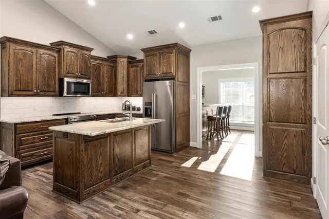 a kitchen with kitchen island a counter top space a refrigerator and a sink