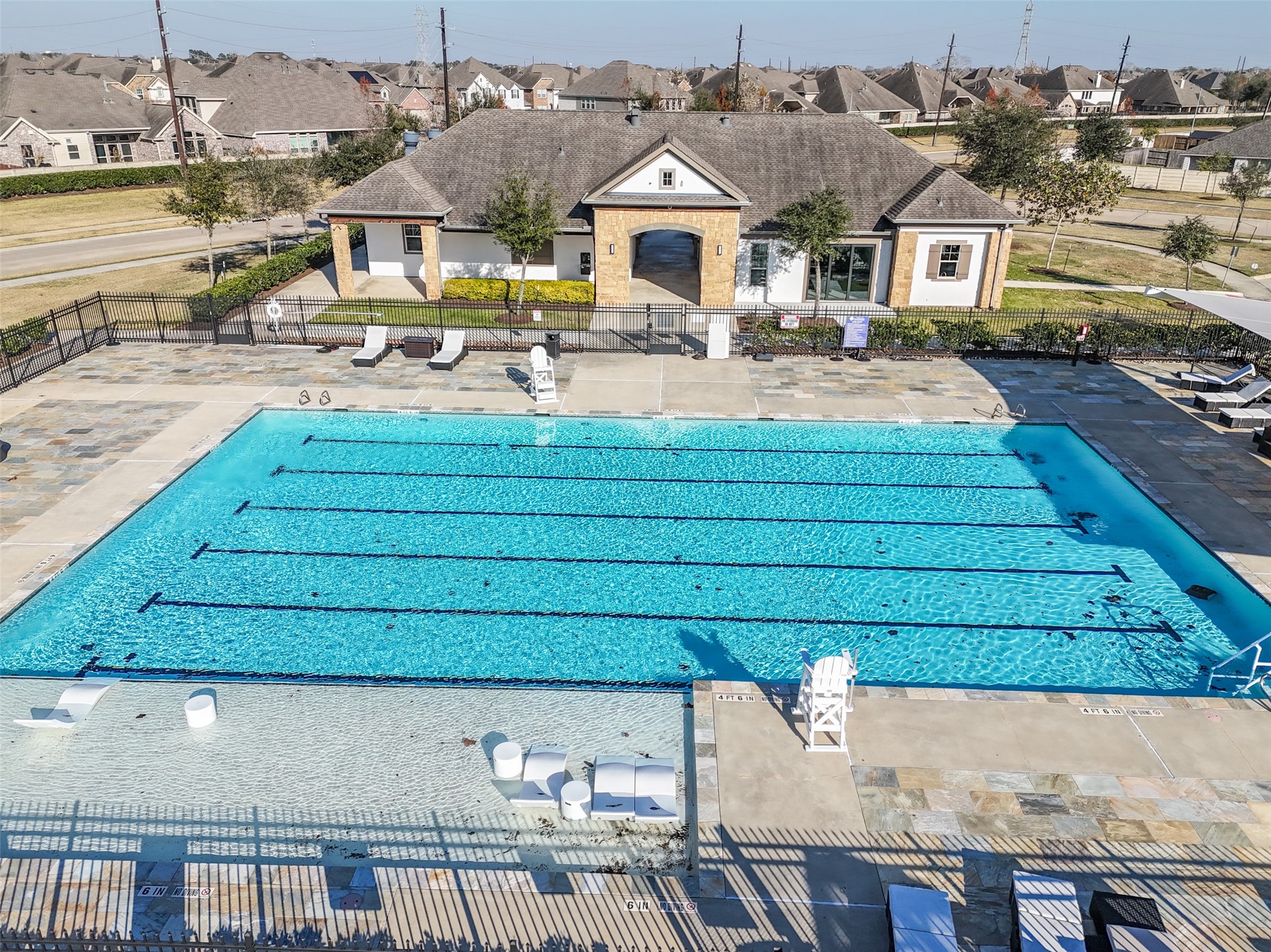 4747 Abercorn Street Rosharon, TX 77583 - Photo 39 of 46 This photo showcases a community swimming pool with clear lanes for swimming, surrounded by a spacious deck with lounge chairs. Adjacent is a charming clubhouse, perfect for relaxation and gatherings. The surrounding neighborhood is visible, featuring well-maintained homes.