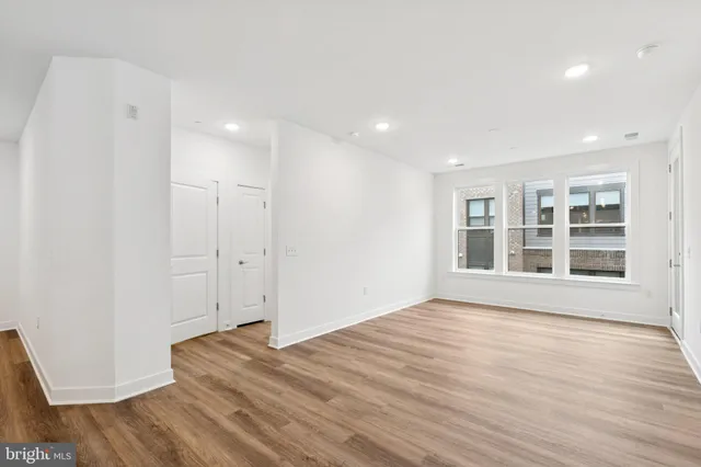 a view of empty room with wooden floor and window