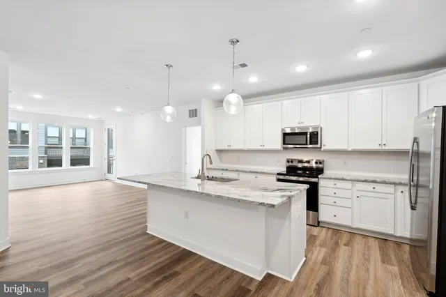 a large kitchen with stainless steel appliances granite countertop a stove a sink and a refrigerator