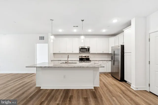 a large kitchen with stainless steel appliances kitchen island a large counter top and a stove top oven