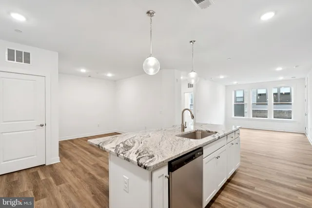a kitchen with granite countertop a sink cabinets and wooden floor