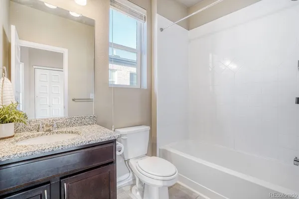a bathroom with a granite countertop toilet a sink and a bathtub