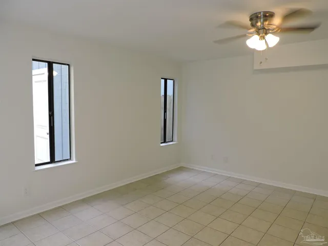 an empty room with windows and fan