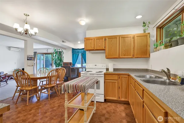a kitchen with stainless steel appliances granite countertop a sink a stove a dining table and chairs with wooden floor