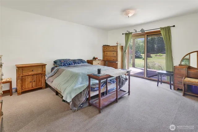 a bedroom with a bed a table and large windows