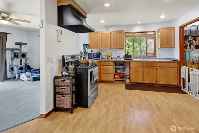 a kitchen with stainless steel appliances kitchen island granite countertop a refrigerator oven a sink dishwasher and a stove with wooden floor