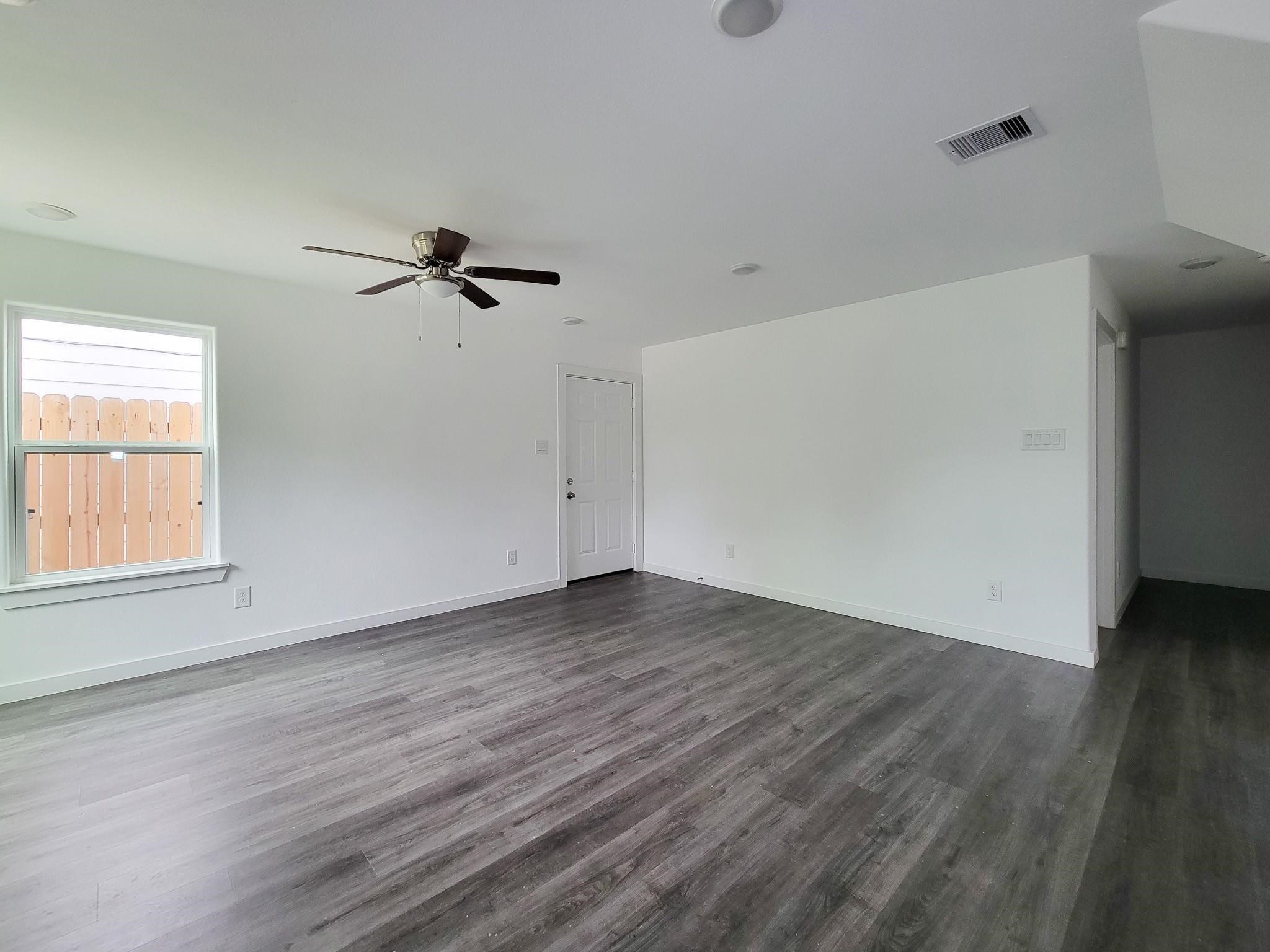 8122 Sterlingshire Street, Unit B Houston, TX 77078 - Photo 2 of 24 an empty room with wooden floor ceiling fan and windows