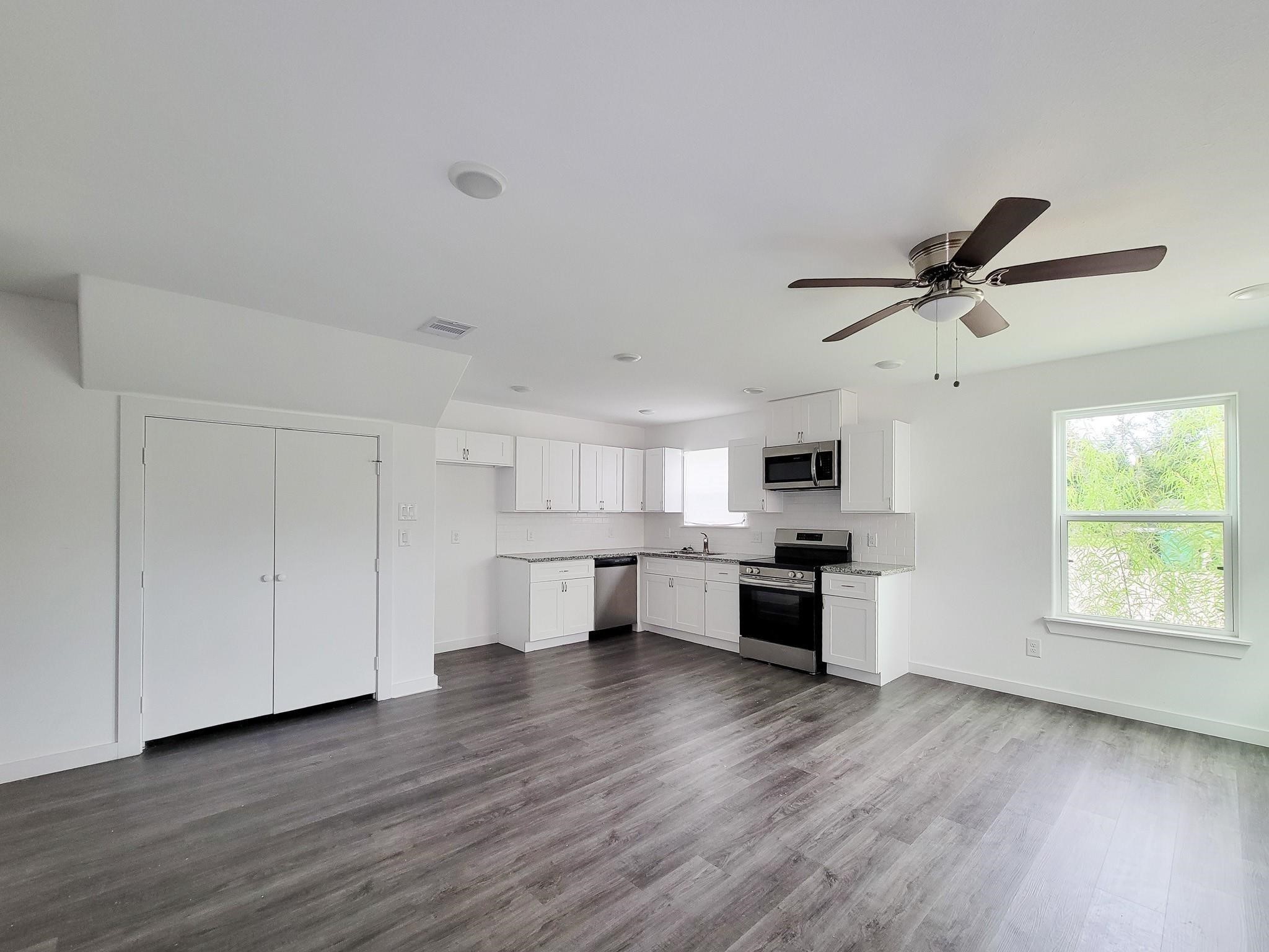 8122 Sterlingshire Street, Unit B Houston, TX 77078 - Photo 4 of 24 a kitchen with kitchen island granite countertop a stove top oven a sink a dining table and chairs with wooden floor