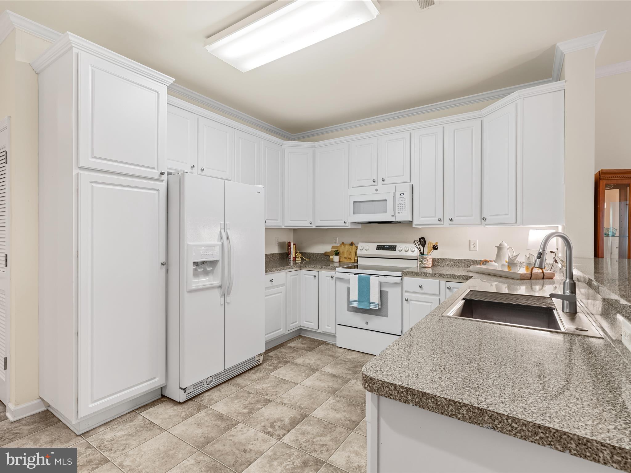 30413 Cedar Neck Road, Unit 304 Ocean View, DE 19970 - Photo 6 of 46 a kitchen with granite countertop white cabinets and refrigerator