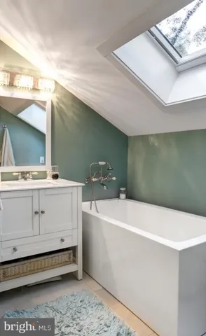 a kitchen with stainless steel appliances granite countertop a sink dishwasher a stove a refrigerator with white cabinets and wooden floor