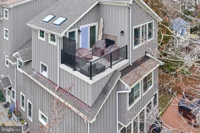 a view of a white house with a yard plants and wooden fence