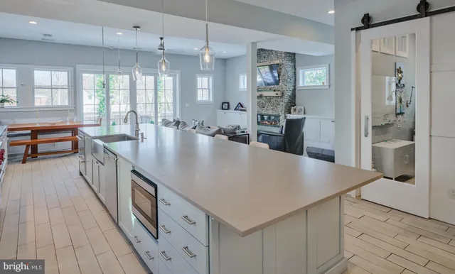 a kitchen with stainless steel appliances kitchen island granite countertop a dishwasher a stove a dining table and chairs with wooden floor