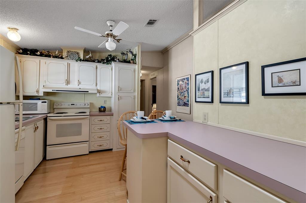 10315 Cortez Road West, Unit 26J Bradenton, FL 34210 - Photo 13 of 69 a kitchen with kitchen island white cabinets stainless steel appliances and a chandelier