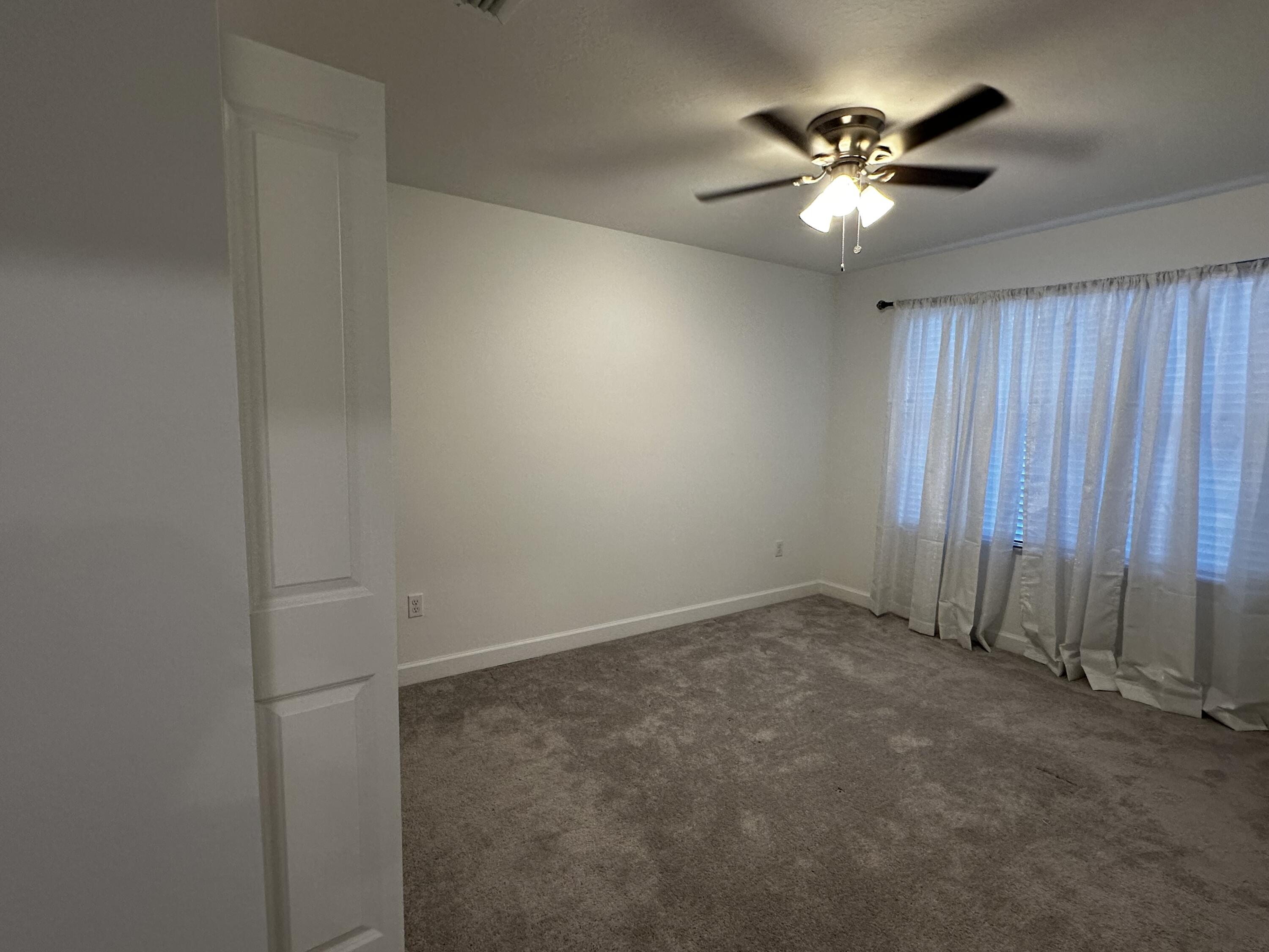 3507 Bauer Road Royal Palm Beach, FL 33411 - Photo 23 of 26 an empty room with a chandelier fan and windows