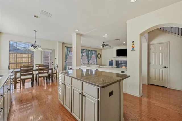 a large kitchen with stainless steel appliances granite countertop a sink dishwasher a stove and a refrigerator with wooden floor