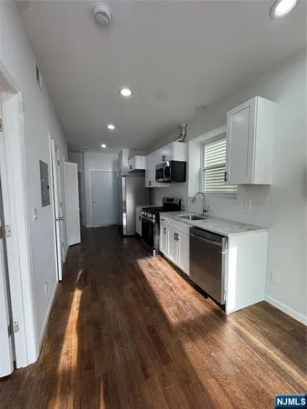 a large kitchen with cabinets wooden floor and stainless steel appliances