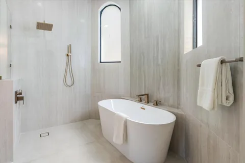 a bathroom with a tub a sink and mirror