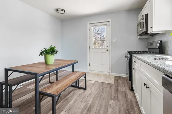 a kitchen with stainless steel appliances granite countertop a table chairs sink and cabinets
