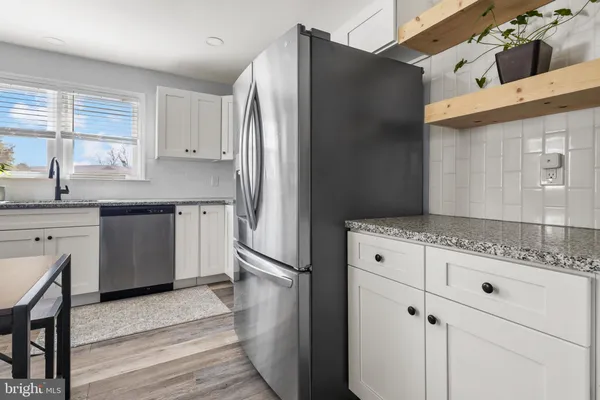 a kitchen room with granite countertop white cabinets and stainless steel appliances