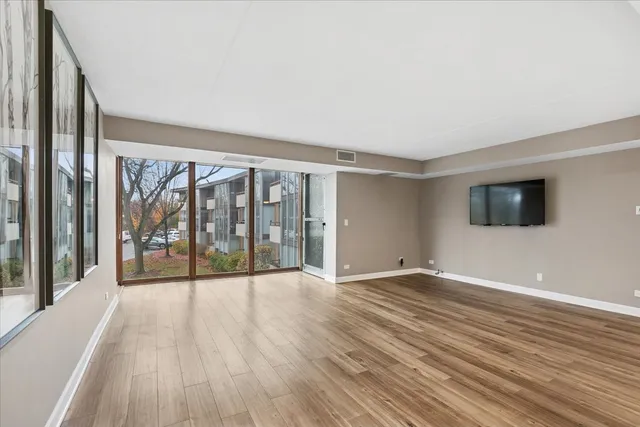 an empty room with wooden floor and windows
