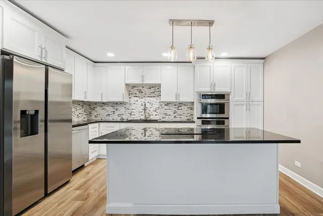 a kitchen with stainless steel appliances granite countertop a sink and a refrigerator