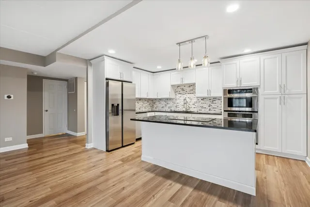 a kitchen with stainless steel appliances kitchen island granite countertop a refrigerator and a stove top oven