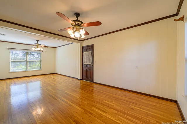 a view of an empty room with wooden floor and a window