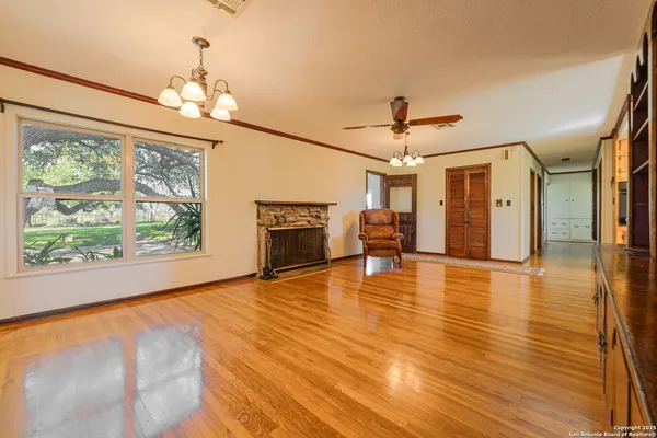 a view of an empty room with a fireplace wooden floor and a chandelier