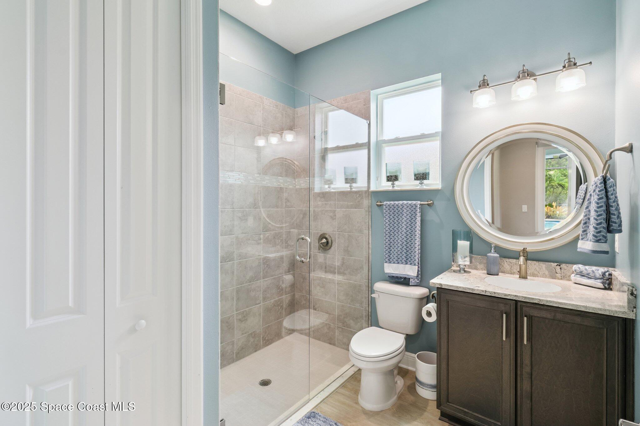 4437 Preservation Circle Melbourne, FL 32934 - Photo 15 of 40 a bathroom with a granite countertop toilet a sink and a mirror