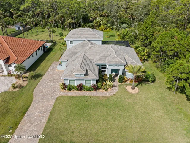an aerial view of a house with swimming pool and large trees