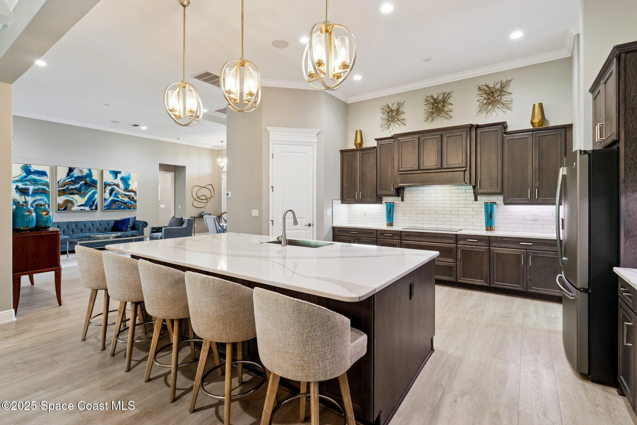 4437 Preservation Circle Melbourne, FL 32934 - Photo 7 of 40 a kitchen with stainless steel appliances kitchen island granite countertop a sink a stove a refrigerator and island with wooden floor