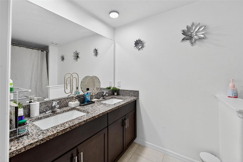 14446 Editors Note Street Ruskin, FL 33573 - Photo 30 of 52 a bathroom with a granite countertop sink a toilet and a mirror