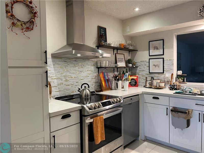 22465 Southwest 61st Way, Unit 241 Boca Raton, FL 33428 - Photo 3 of 18 a kitchen with stainless steel appliances granite countertop a sink stove and cabinets