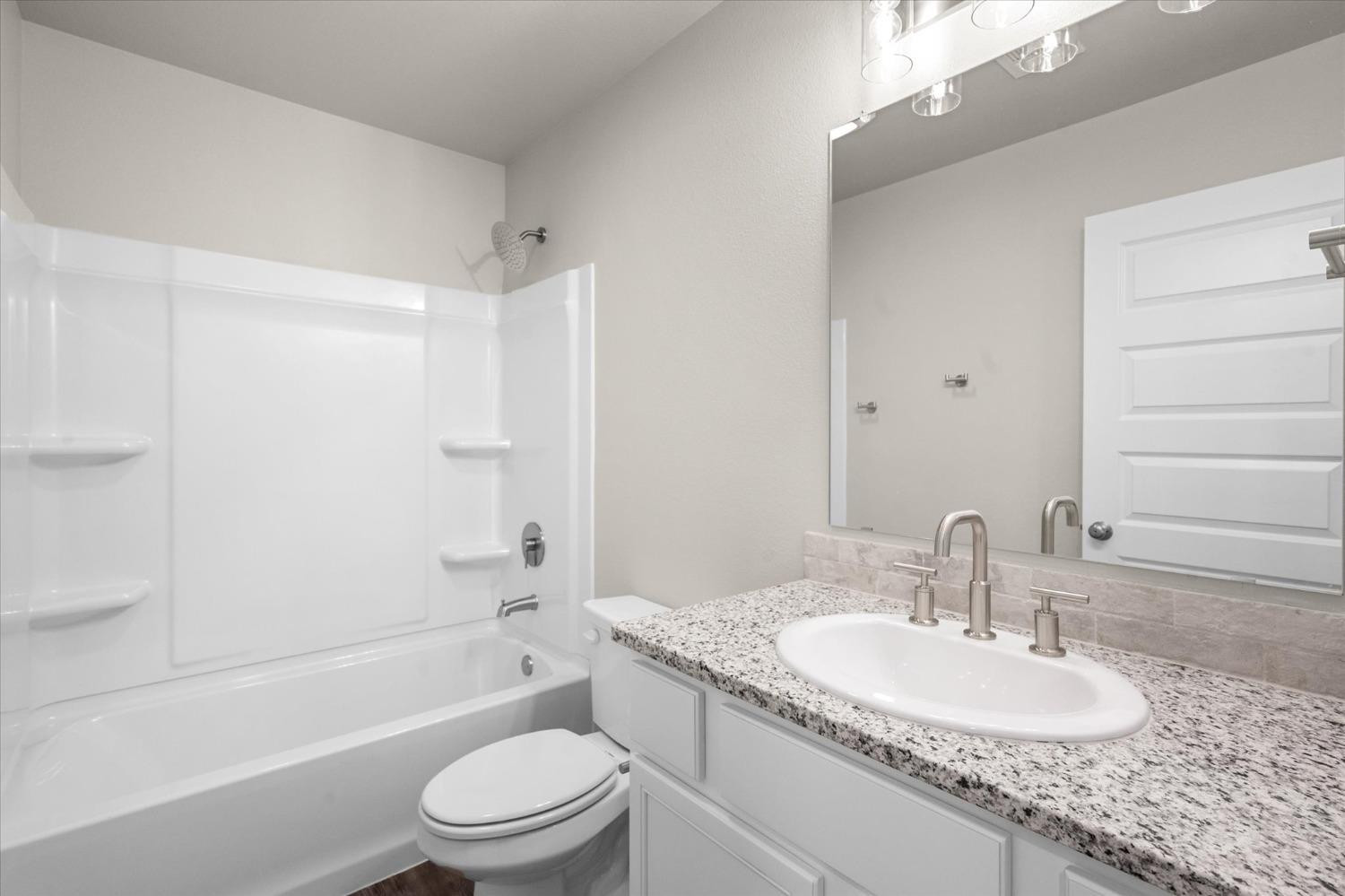 1608 142nd Street Lubbock, TX 79423 - Photo 17 of 20 a bathroom with a granite countertop sink toilet and shower