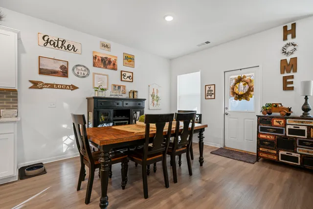 a kitchen with stainless steel appliances granite countertop a dining table chairs refrigerator and sink