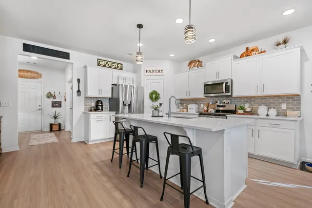 a kitchen with stainless steel appliances granite countertop a stove a refrigerator a microwave oven a sink with island and chairs with wooden floor