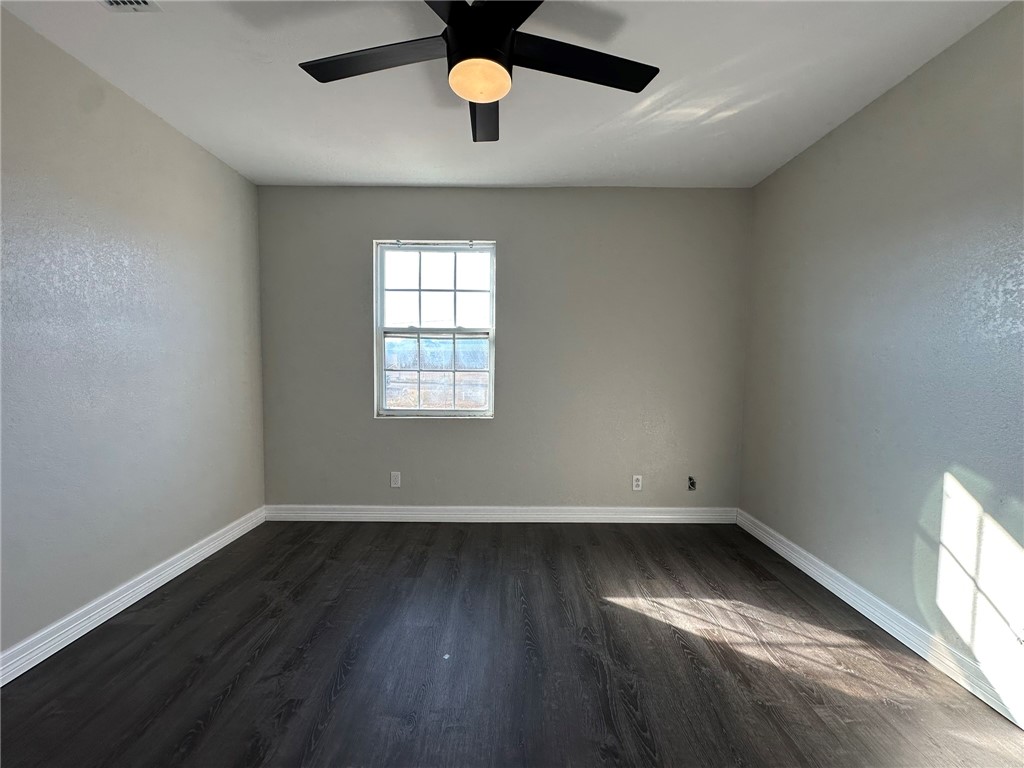 3152 Meadow Lane Robstown, TX 78380 - Photo 26 of 40 an empty room with wooden floor chandelier fan and windows