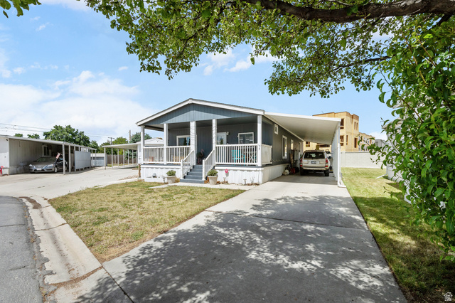150 West 7500th South, Unit 13 Midvale, UT 84047 - Photo 28 of 32 Property exterior featuring a covered front porch with white railing, gray siding, and a paved driveway leading to a car port
