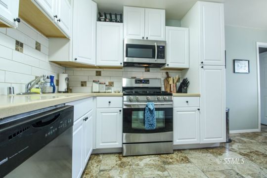 708 West Perdew Avenue Ridgecrest, CA 93555 - Photo 10 of 37 a kitchen with stainless steel appliances granite countertop a stove a sink and a microwave
