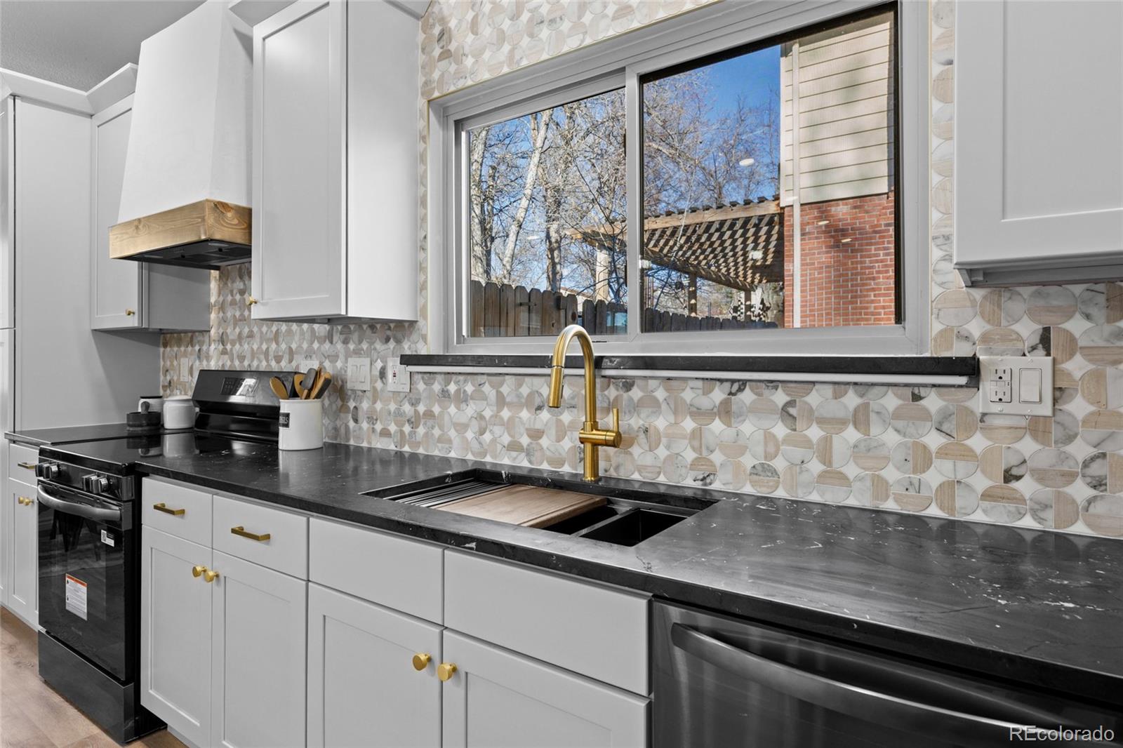 8205 Dudley Way Arvada, CO 80005 - Photo 8 of 44 a kitchen with stainless steel appliances granite countertop a sink a stove and white cabinets