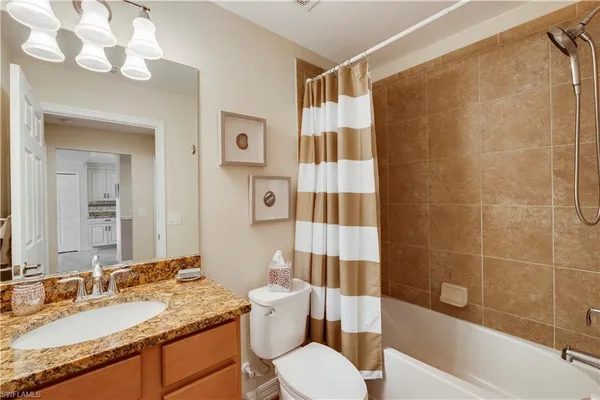 a bathroom with a granite countertop sink toilet a mirror a vanity and shower