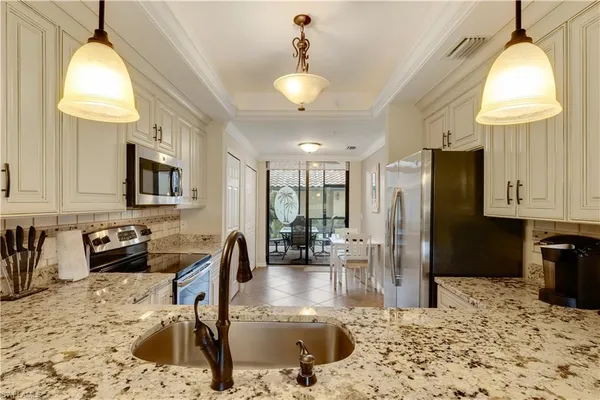 a kitchen with granite countertop a stove a refrigerator and a sink