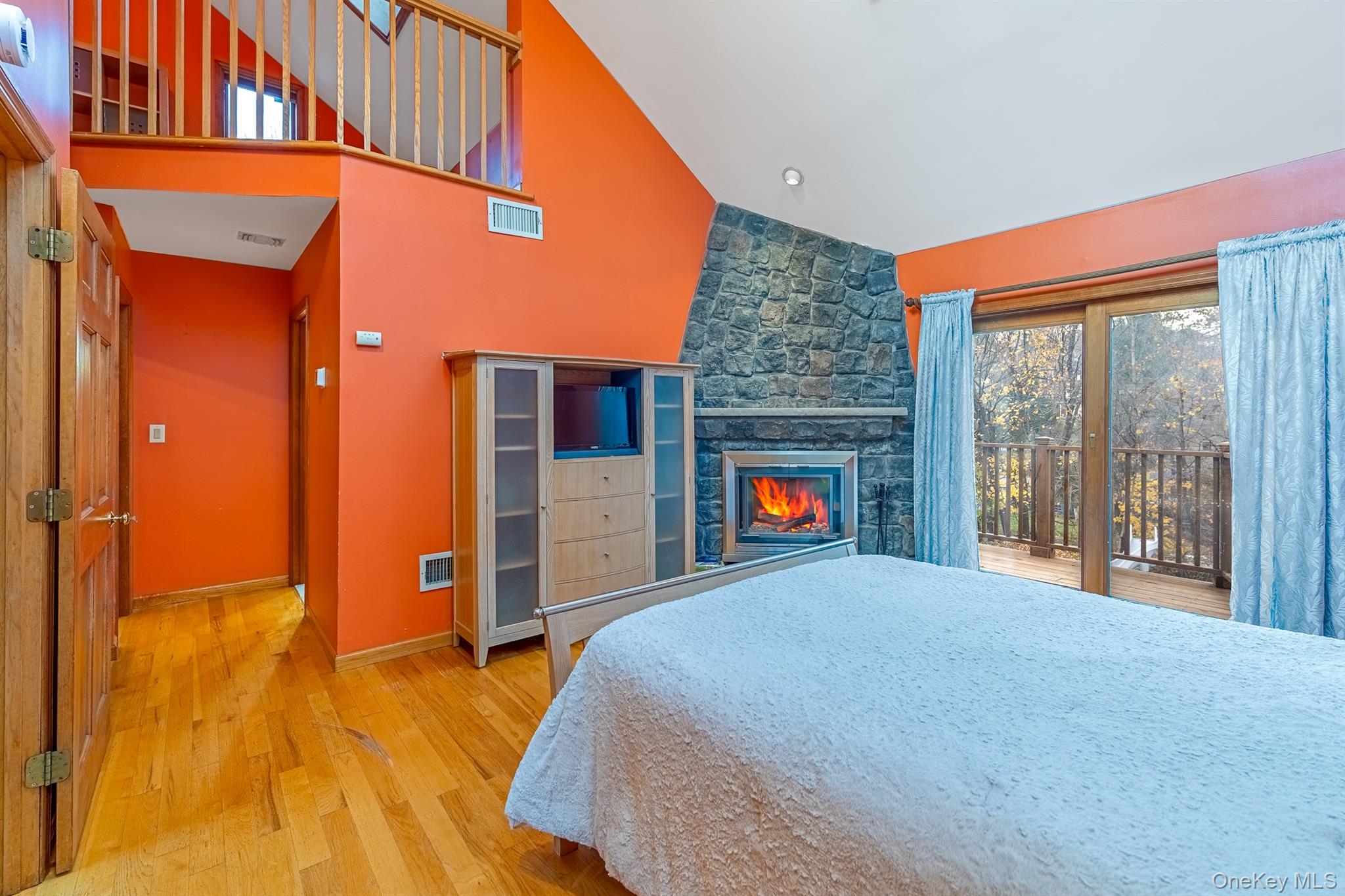 22 Weyant Road Fort Montgomery, NY 10922 - Photo 19 of 26 Bedroom with multiple windows, light wood-type flooring, access to exterior, a stone fireplace, and high vaulted ceiling