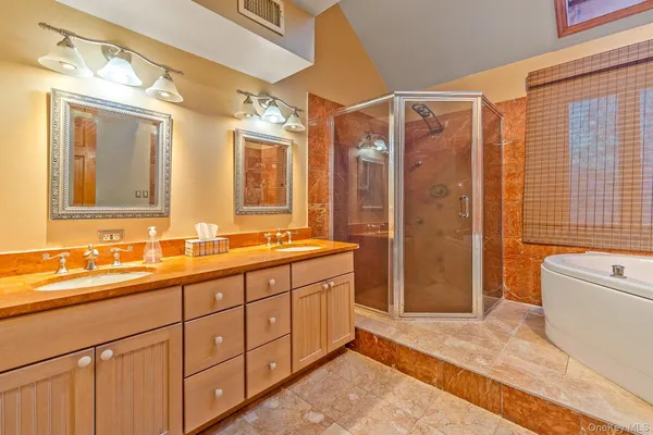 a spacious bathroom with a double vanity sink a large mirror and a shower