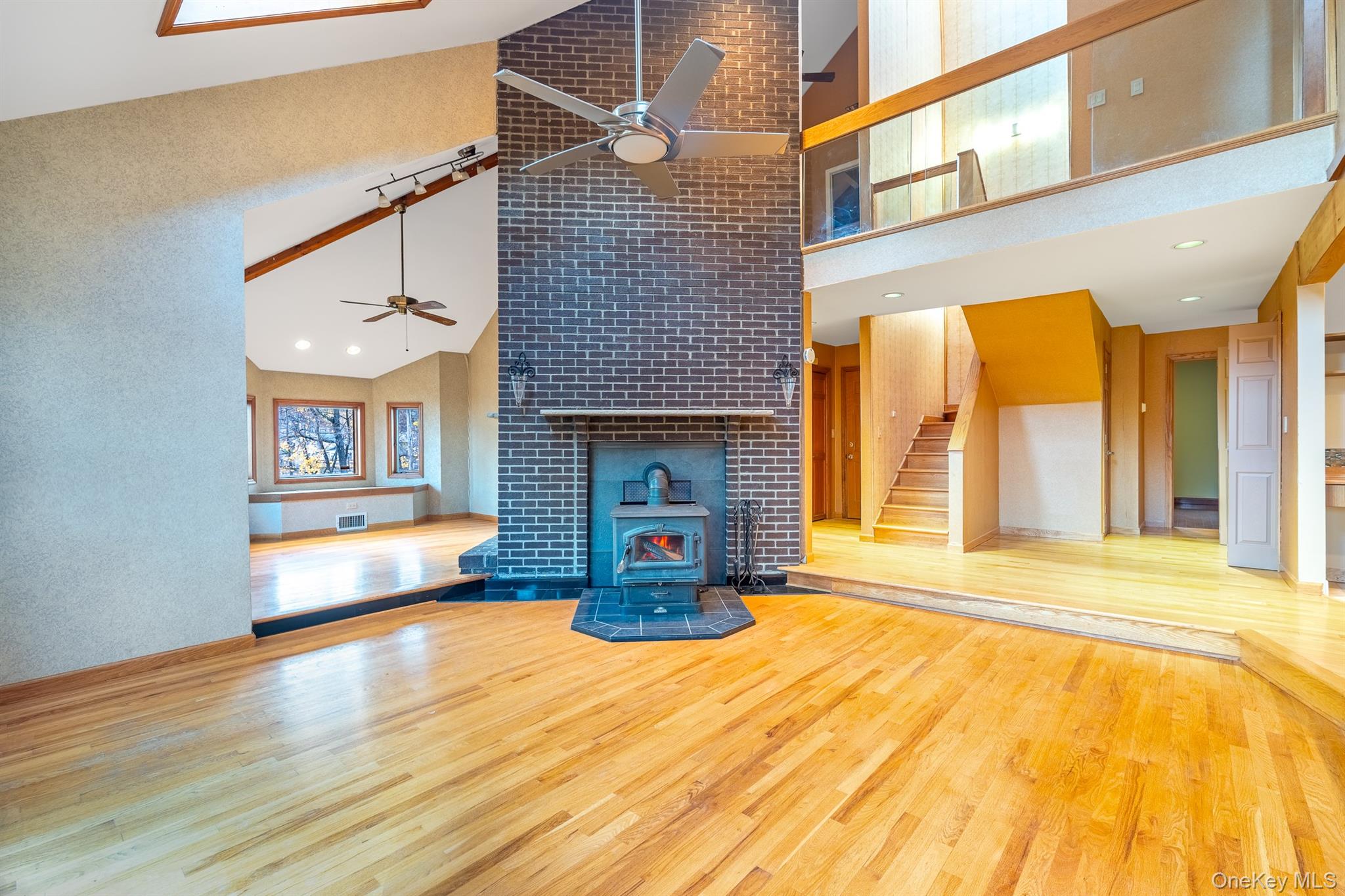 22 Weyant Road Fort Montgomery, NY 10922 - Photo 8 of 26 Unfurnished living room featuring wood finished floors, a wood stove, stairs, high vaulted ceiling, and recessed lighting