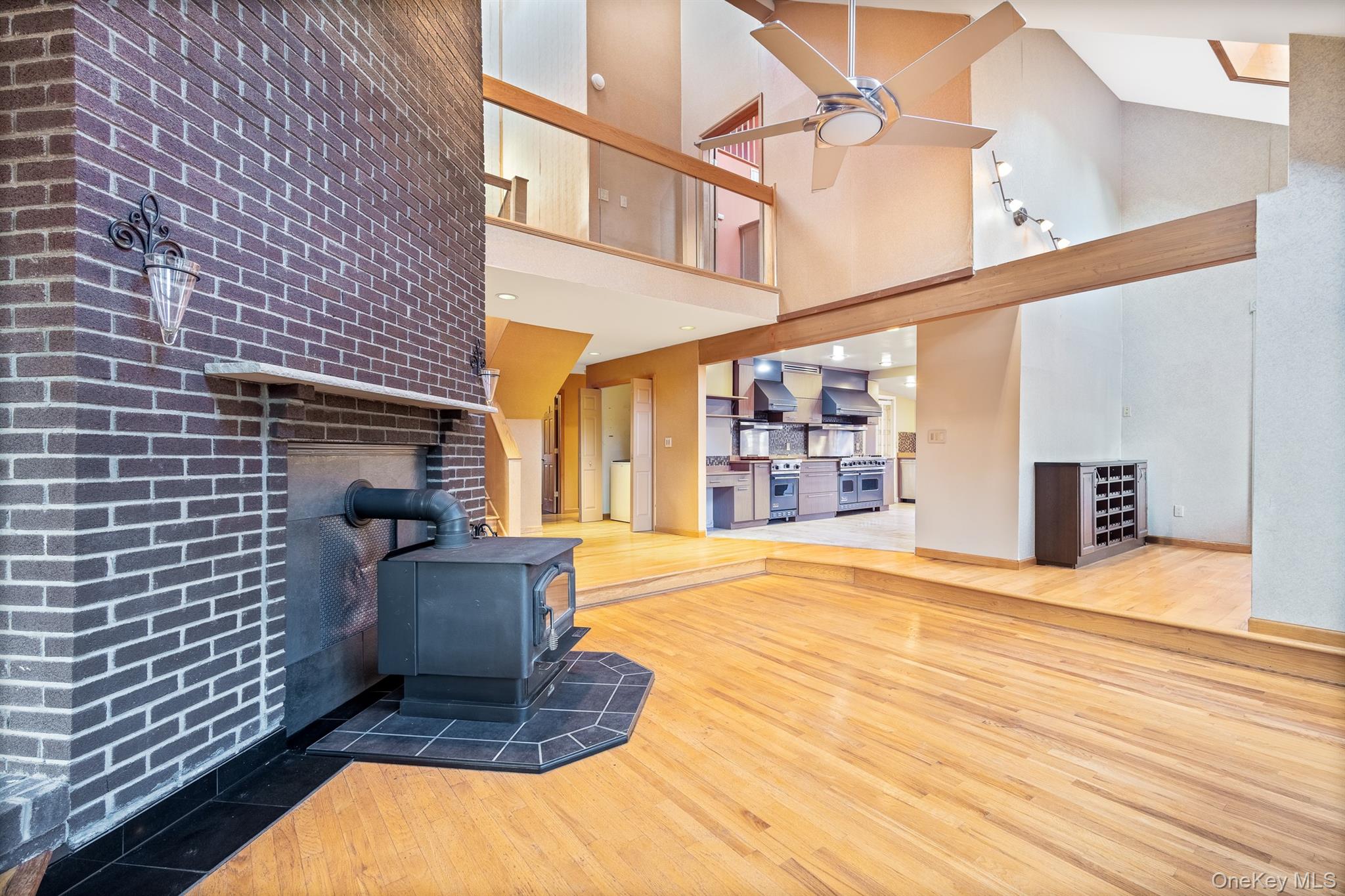 22 Weyant Road Fort Montgomery, NY 10922 - Photo 9 of 26 Unfurnished living room with a wood stove, brick wall, wood-type flooring, a high ceiling, and ceiling fan