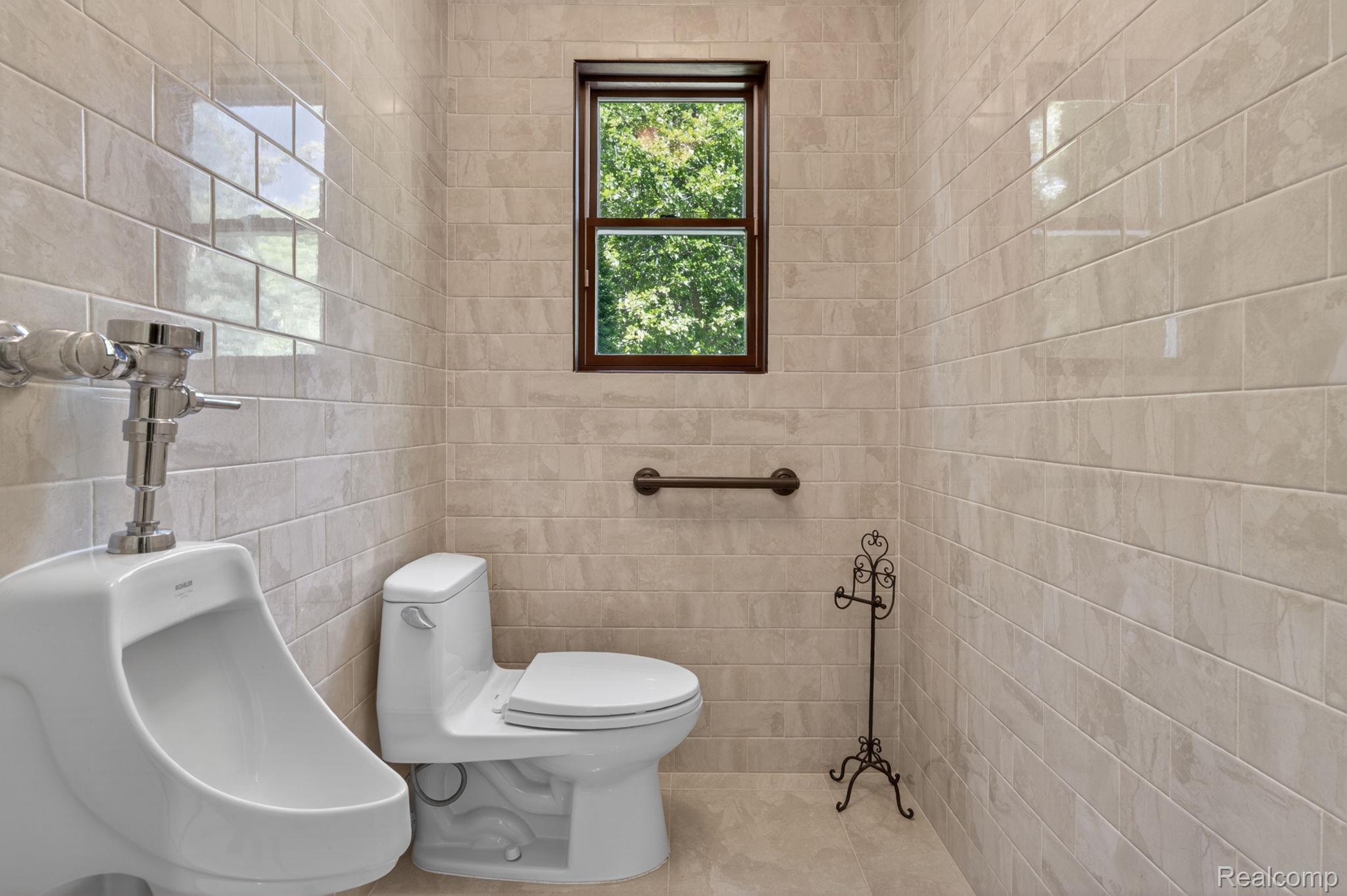 9353 Hill Road Swartz Creek, MI 48473 - Photo 57 of 98 Fully tiled restroom featuring a window with dark wood trim, white porcelain toilet, and a grab bar