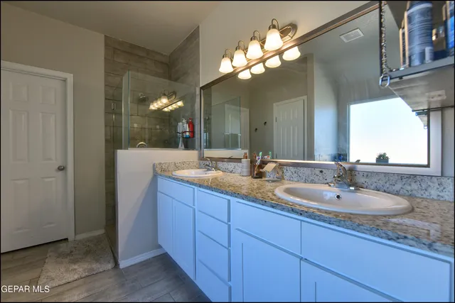 a bathroom with a granite countertop sink a large mirror and a shower